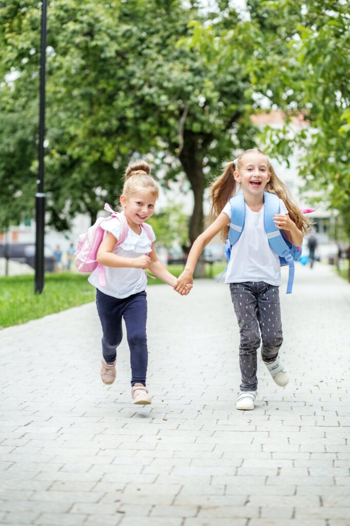 Funny children run from school with backpacks. The concept of school, study, education